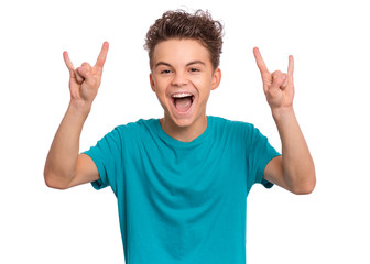 Portrait of funny teen boy making Rock Gesture, isolated on white background. Beautiful caucasian young teenager showing horns up gesture. Happy cute child screaming and doing heavy metal rock sign. - 316958717