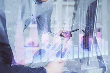 Double exposure of chart with businessman typing on computer in office on background. Concept of...