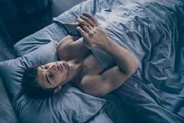 High angle above view photo of handsome homey macho guy lying morning bed alone holding telephone...