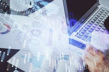 Double exposure of stock graph with businessman typing on computer in office on background. Concept of hard work.