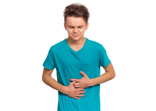 Portrait of teen boy with stomachache, isolated on white background. Caucasian young teenager with hands on stomach. Child having terrible pain in stomach. Diarrhea or gastroenteritis health problem.