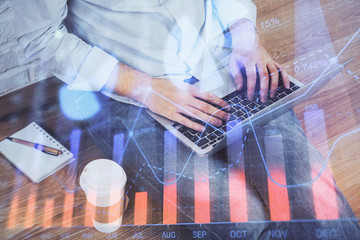 Forex graph with businessman working on computer in office on background. Concept of analysis. Double exposure.