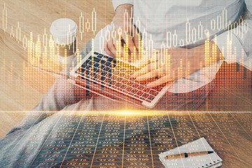 Forex graph with businessman working on computer in office on background. Concept of analysis. Double exposure.