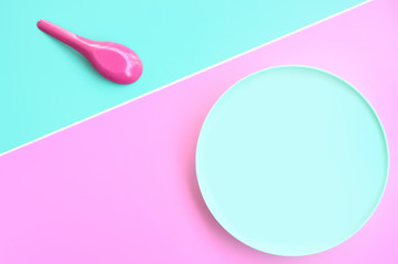Set of a blue plate with spoon on pink and blue background