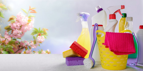Basket with cleaning tools and products on blurry spring background. Spring cleaning, eco natural cleaning products concept. Copy space