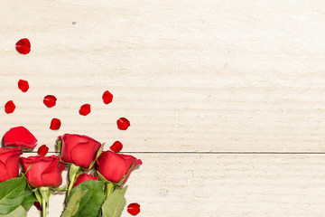 Red roses and rose petals on a wooden table