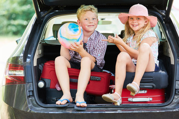 Geschwister sitzen auf Gepäck im Auto