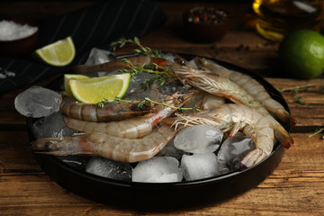 Fresh raw shrimps with ice on wooden table