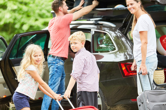 Familie und Kinder beim Koffer packen auf Auto
