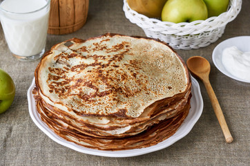 Stack of thin pancakes on a brown textile background