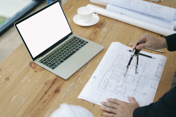 Top view, Architect or engineer hands working on blueprint plans with a dividers, pencil ,laptop a ruler, calculator, and engineering tools. Architect or engineer working on blueprint in office.