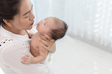 Young mother holding her baby. Portrait of Asian young with her happy child on arms on white background.