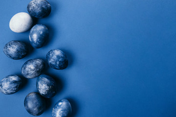 Beautiful group ombre blue Easter eggs with quail eggs and feathers on a blue background. Easter concept. Border eggs. Copy space for text