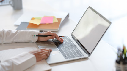 Close up view of businesswoman typing on blank screen laptop