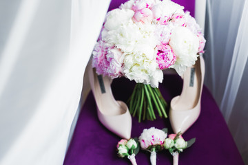 Pair of elegant and stylish bridal shoes with a bouquet with roses and other flowers