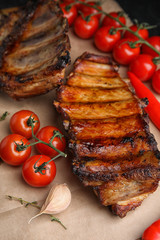 Tasty grilled ribs with tomatoes on table