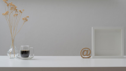 Cropped shot of workspace with mock up frames, coffee cup and decorations on white wooden table
