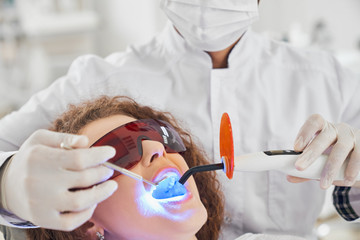 Attractive lady doing whitening procedure in dental clinic