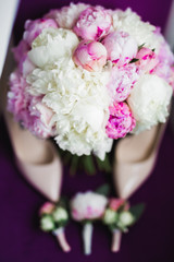 Pair of elegant and stylish bridal shoes with a bouquet with roses and other flowers
