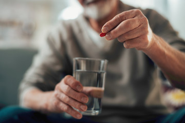 Close up of old man taking pills. Senior man drinking medicine. 