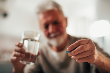 Close up of old man taking pills. Senior man drinking medicine. 