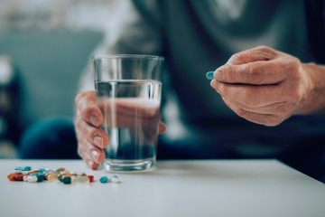 Close up of old man taking pills. Senior man drinking medicine. 