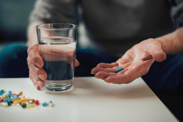 Close up of old man taking pills. Senior man drinking medicine. 