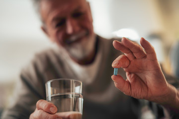 Close up of old man taking pills. Senior man drinking medicine. 