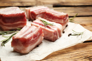 Raw ribs with rosemary on wooden table, closeup