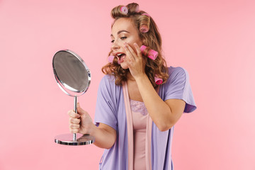 Image of happy young woman touching her face and holding mirror