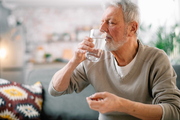 Old man taking pills. Close up of senior man drinking medicine. 