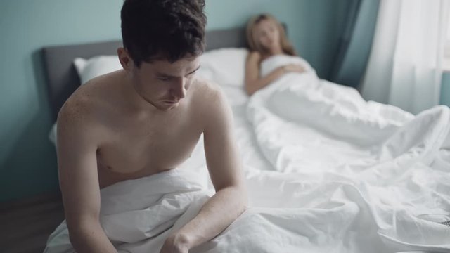 Heterosexual couple having problem in bed. Man sitting back to a woman. Marriage, family, love, sex concept. Filmed on REd 4k, 10 bit color