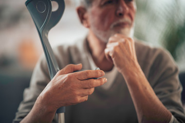 Old man with crutches. Senior man having pain.