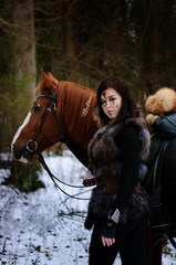 a Viking girl next to a red horse painted in black runes.