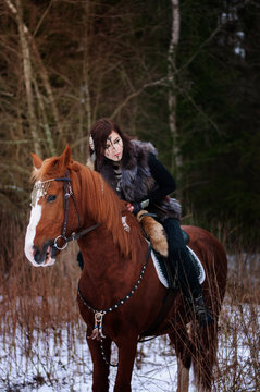 a Viking girl riding a red horse painted in black runes