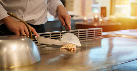 Japanese chef cooking meat in teppanyaki restaurant