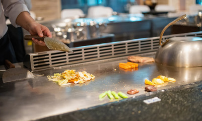 Japanese chef cooking meat in teppanyaki restaurant