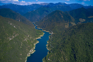 Fototapeta na wymiar Aerial view, Lake Valvestino, Italy. Beautiful lake between the mountains. Cumulus clouds, blue sky
