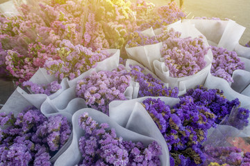The flowers bouquet for sale are wrapped in the white paper in the market. 