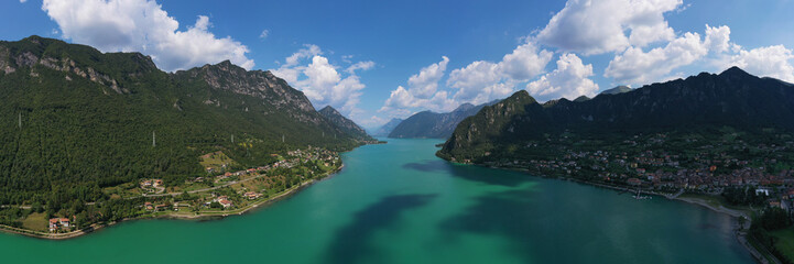 Panoramic view of the mountains and Lake Idro.  Reflection in the water of the mountains, trees, blue sky. Aerial view, drone photo - Powered by Adobe
