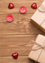 gifts on a wooden table. Close to sweets and candles. There is a text. Valentine's day celebration concept. vertical image