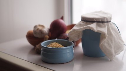 clay jugs, saucers with cereals, onions and garlic on the background of the window