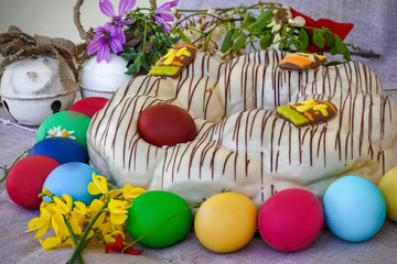 A traditional white chocolate sweet (brioche) coated between dyed Easter eggs and spring flowers