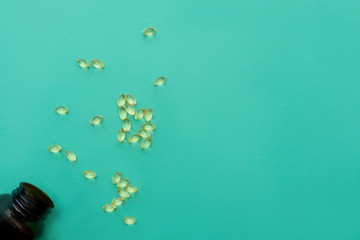Fototapeta premium Vitamin D bottle with spilled contents on turquoise