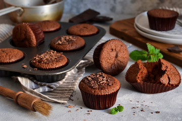 Chocolate muffins with chocolate moss sauce and mint on a concrete background.