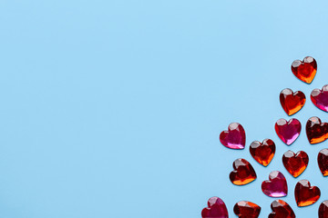 red glass hearts on a blue background in the corner with space for text.