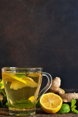 Hot tea with ginger, mint and lemon on a brown concrete background. Horizontal focus.