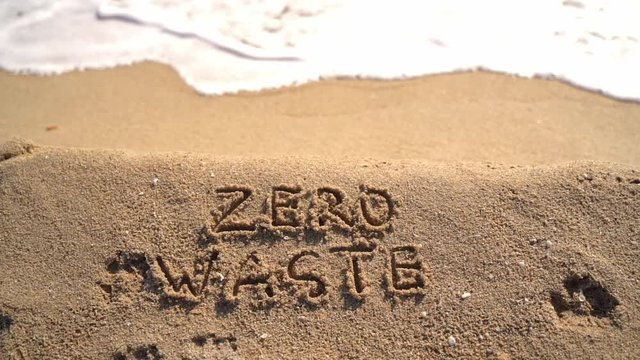Text Zero waste handwritten on sand on the sea beach. Climate change ecology problem