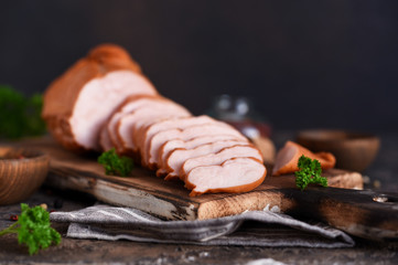 Smoked ham with spices on a wooden board. Concrete background.