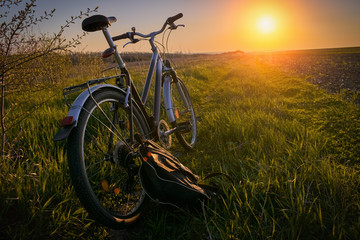 Fototapeta na wymiar Bicycle in a field outside the city against the sunset sky: the concept of rest and outdoor activities